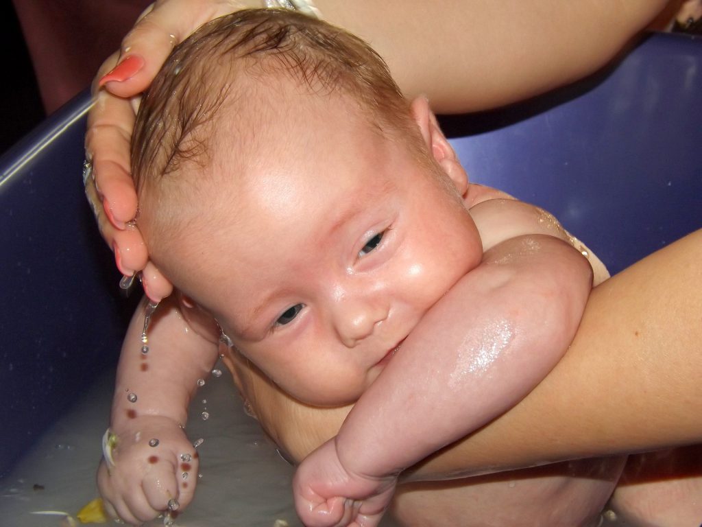 bañando a un bebé en una bañera azul